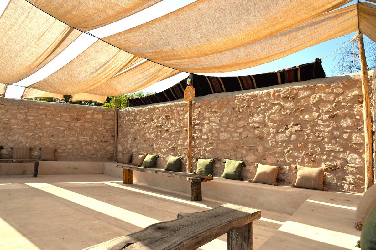 A shaded linen-canopied terrace with cushioned benches at the Morocco retreat villa